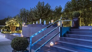 A set of outdoor stairs with a glass railing, surrounded by greenery and decorative lighting. - LHP Hotel Montecatini Palace & SPA (Montecatini Terme)