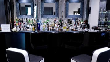 A bar area with multiple liquor bottles, a mirror, and two chairs.