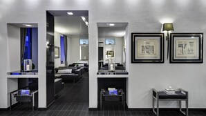 A modern hotel lobby with a central seating area, framed artwork on the walls, and a small table with a lamp. - LHP Hotel Montecatini Palace & SPA (Montecatini Terme)