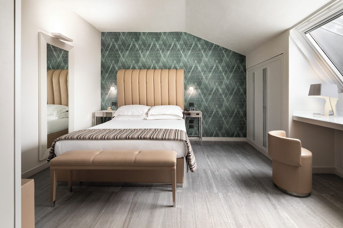 Quarto moderno com uma cama grande, um banco, uma escrivaninha e um espelho.