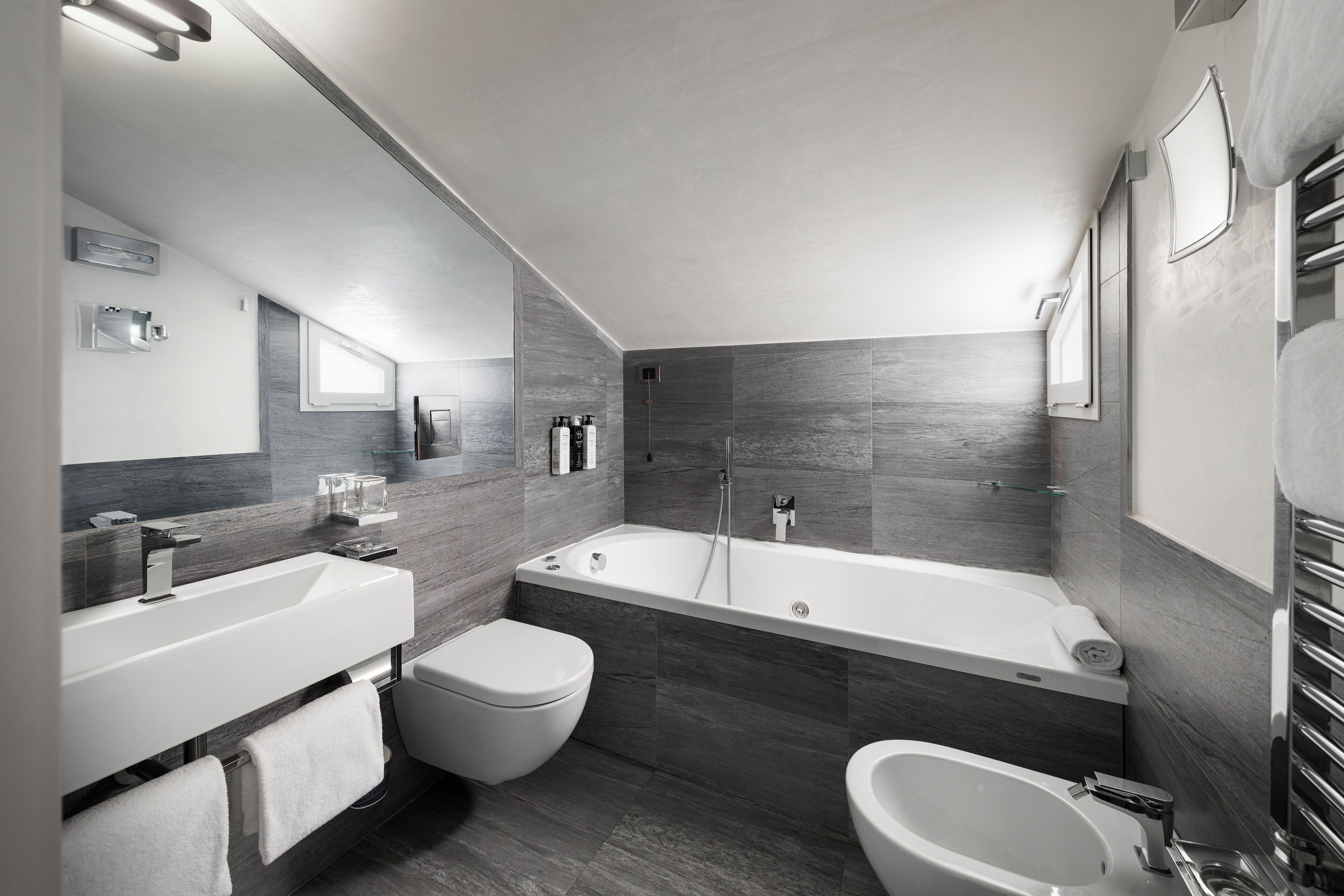 A modern bathroom with a large bathtub, a separate shower area, and a bidet.