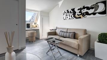 A modern living room with a beige sofa, a glass coffee table, and a large abstract painting on the wall.