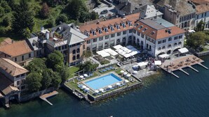 Vista aèria d'un edifici històric amb un gran pati, una piscina i un moll que s'estén sobre l'aigua.