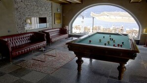 Taula de bitlles en una habitació amb pared de pedra i vista al mar.