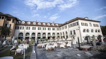 A courtyard with outdoor seating and a building with multiple floors and arched windows.