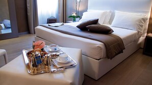 Una habitació d'hotel amb un llit ben arrenjat, una bandeja amb articles per esmorzar i una taula de nit.