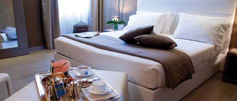 A hotel room with a neatly made bed, a tray with breakfast items, and a bedside table.