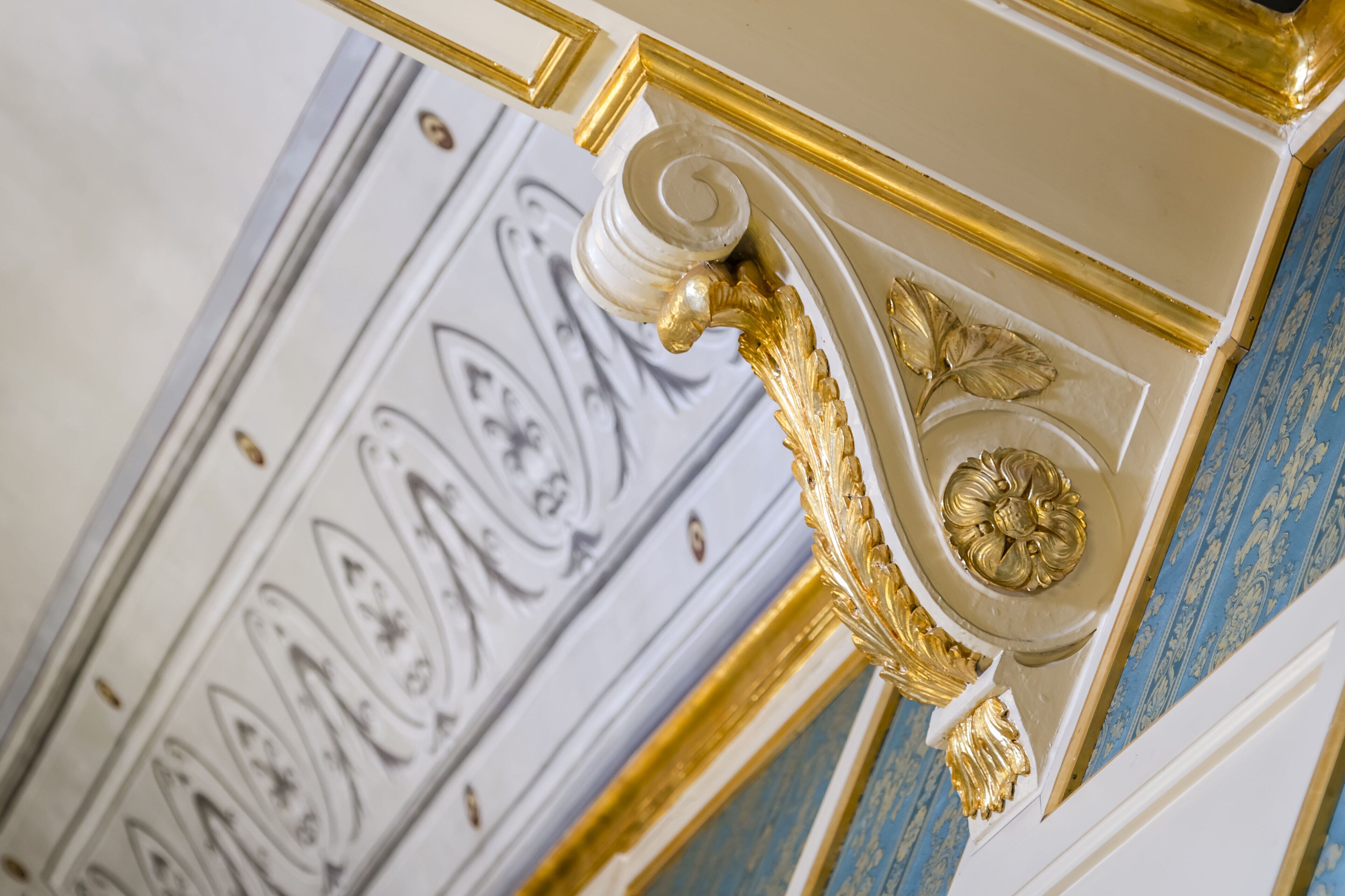 A close-up of ornate wall molding with gold accents and a decorative panel with intricate designs.