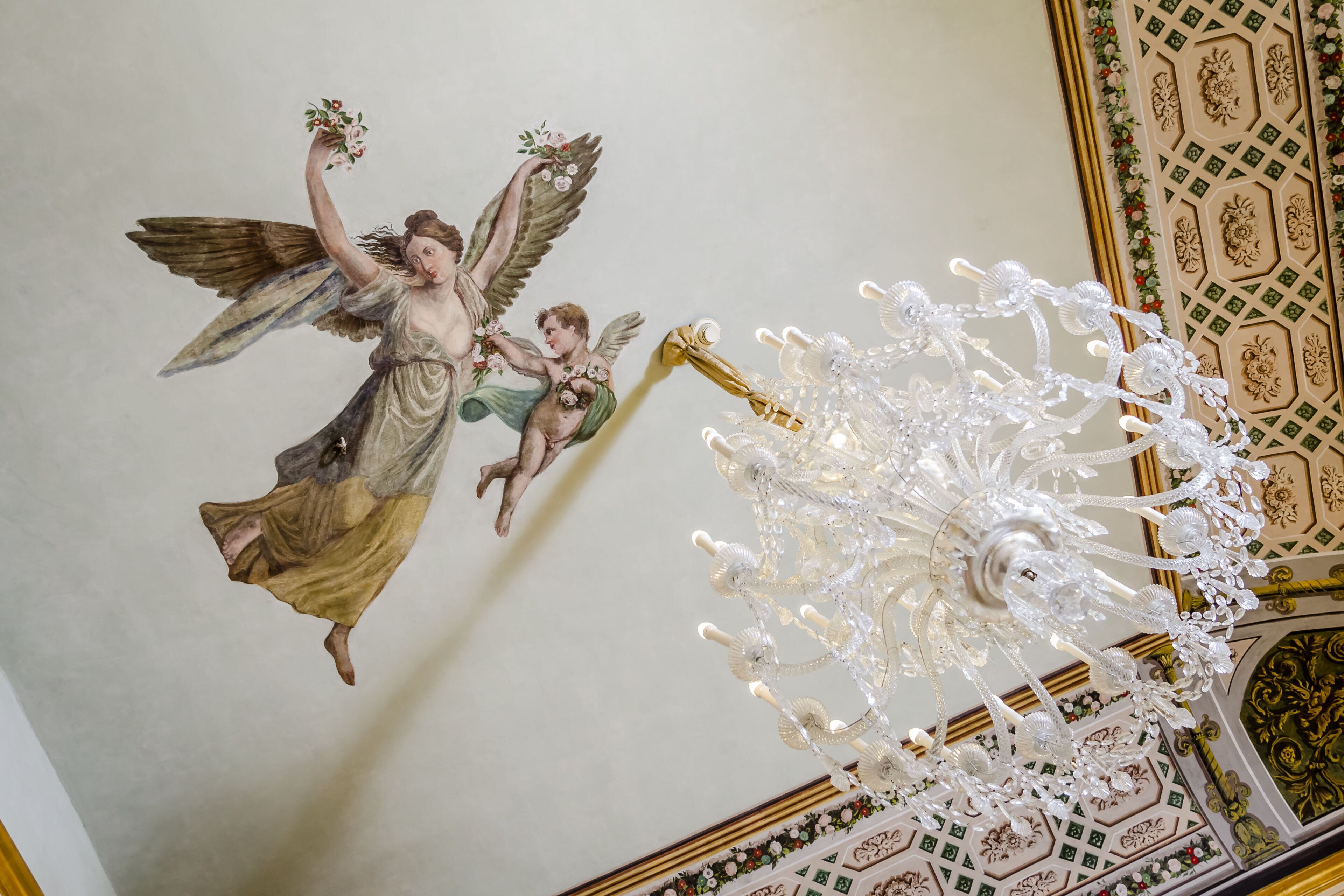 Eine Decke mit Wandgemälde eines Engels und einer Chandelier.