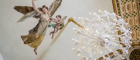 Eine Decke mit Wandgemälde eines Engels und einer Chandelier.