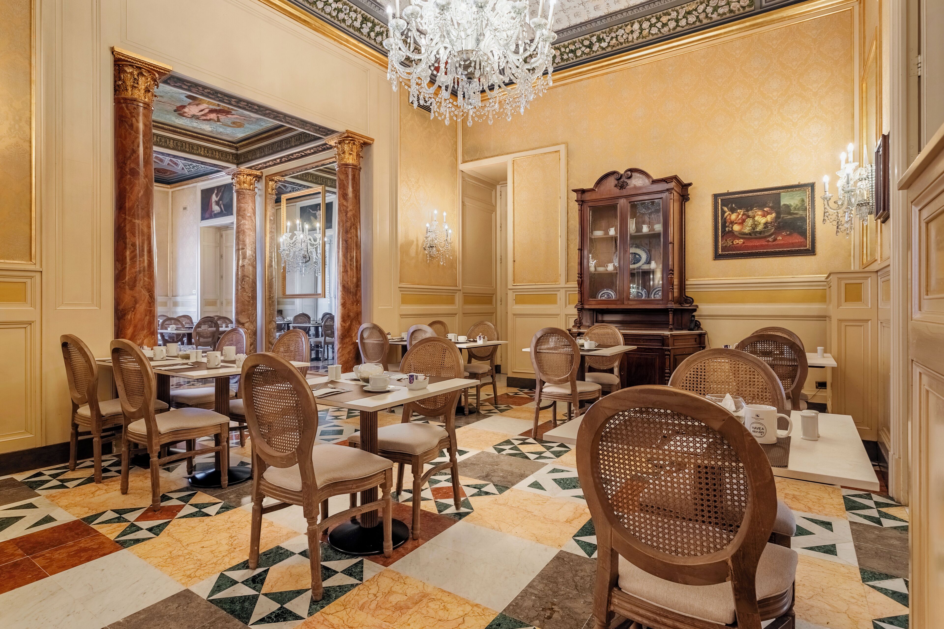 A formal dining room with wooden chairs, a chandelier, and a patterned floor.