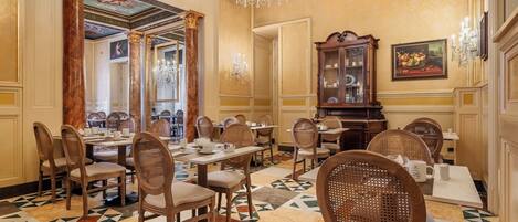 A formal dining room with wooden chairs, a chandelier, and a patterned floor.