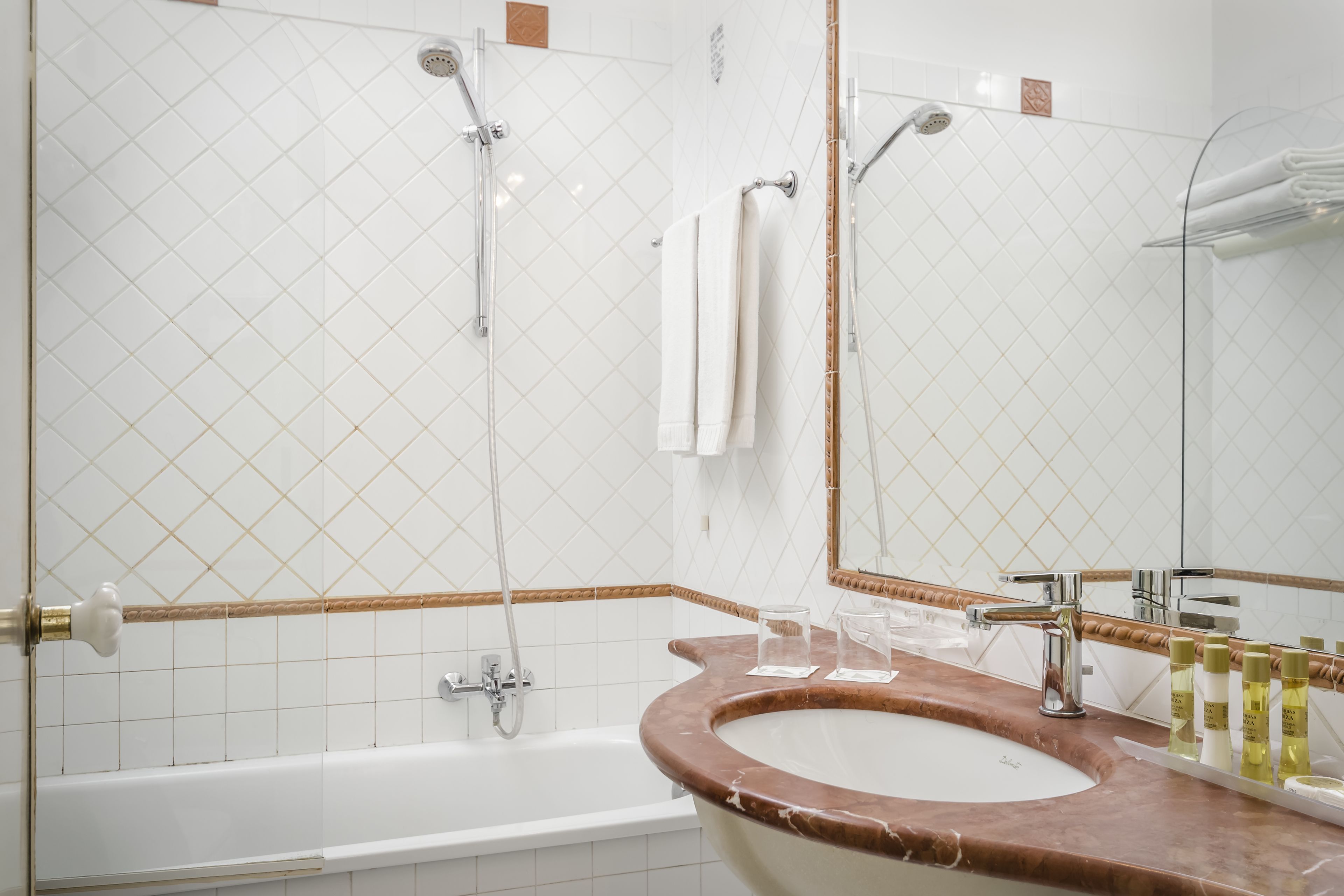 A bathroom with a bathtub, a sink with a marble countertop, and a large mirror.