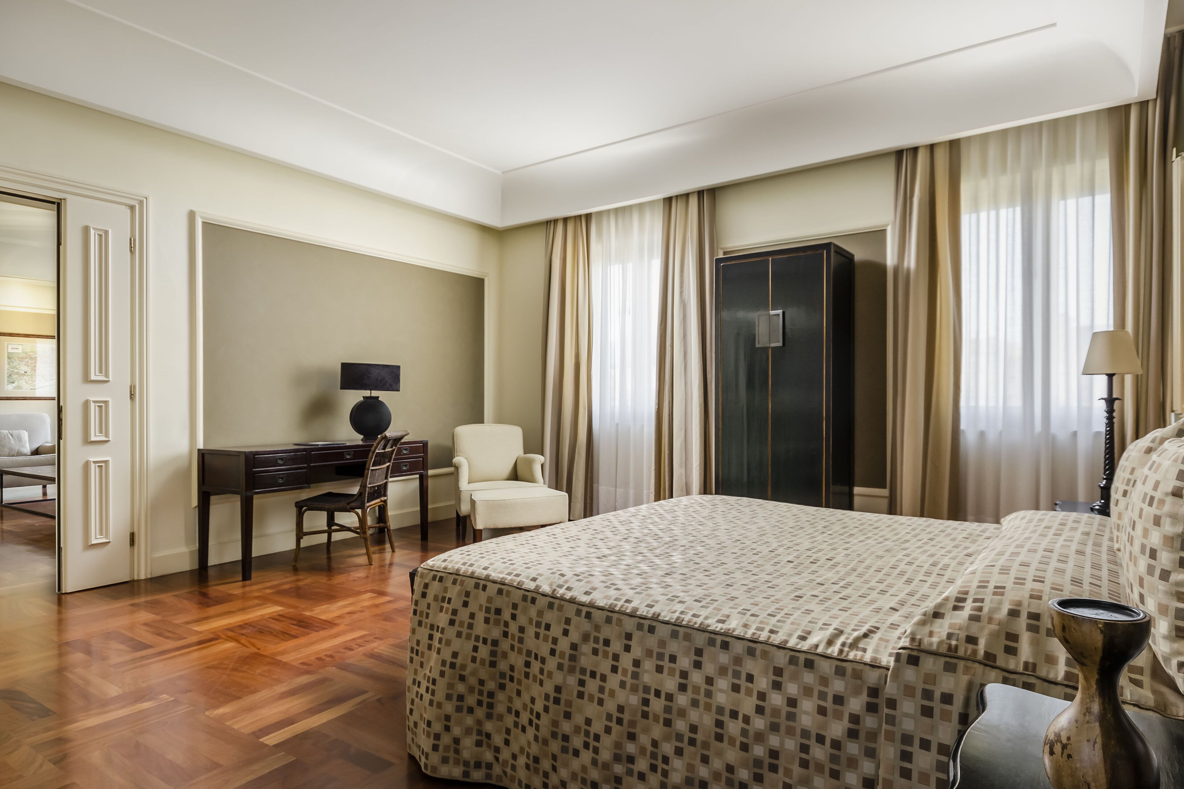 Een hotelkamer met een groot bed, een bureau met stoel, een kledingkast en een lamp.