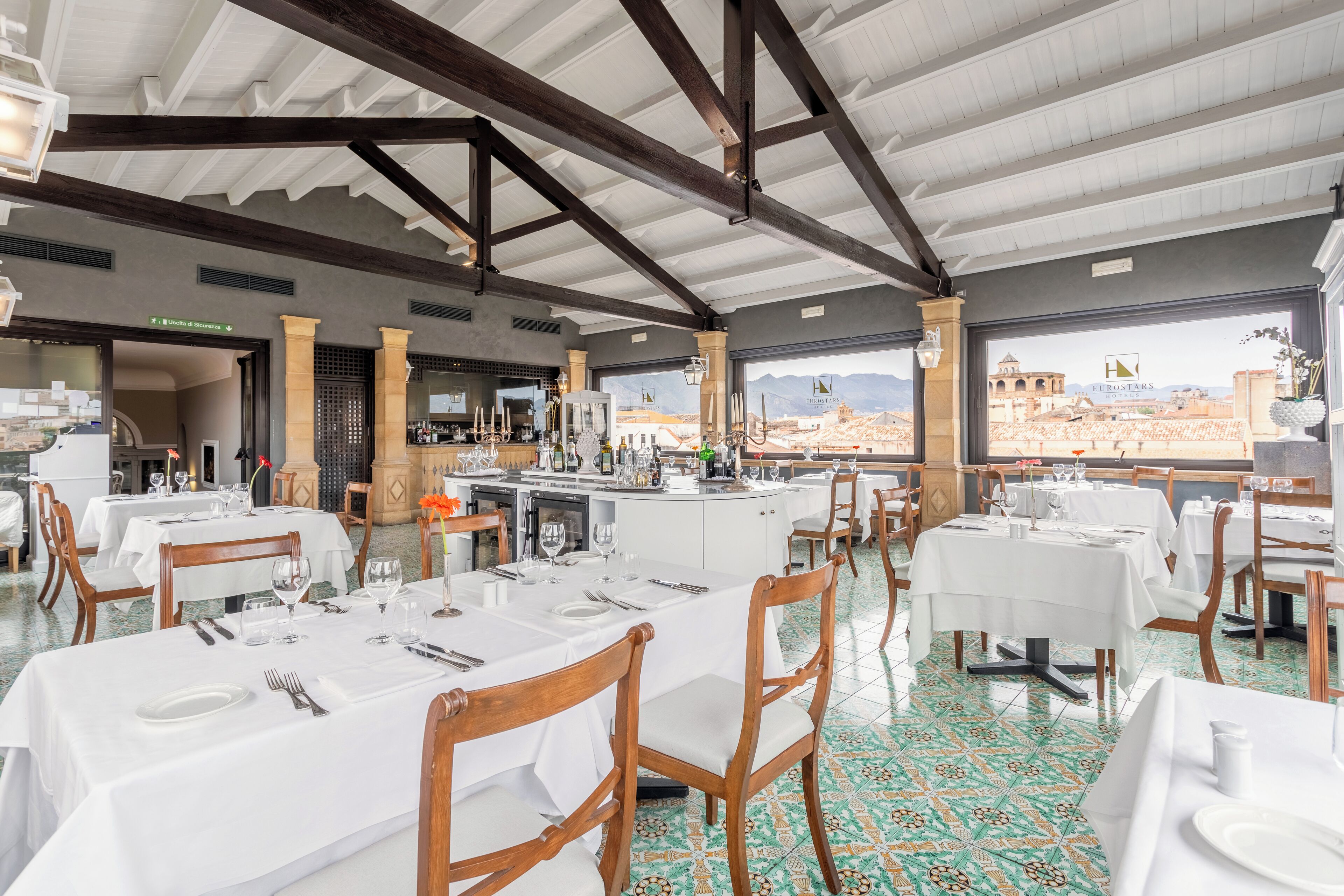 Ein Restaurant mit gedeckten Tischen, einer Küche und Blick auf eine Berglandschaft.