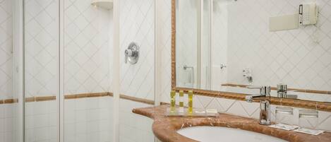 Un baño con lavamanos de mármol, espejo, cabina de ducha y toallero.