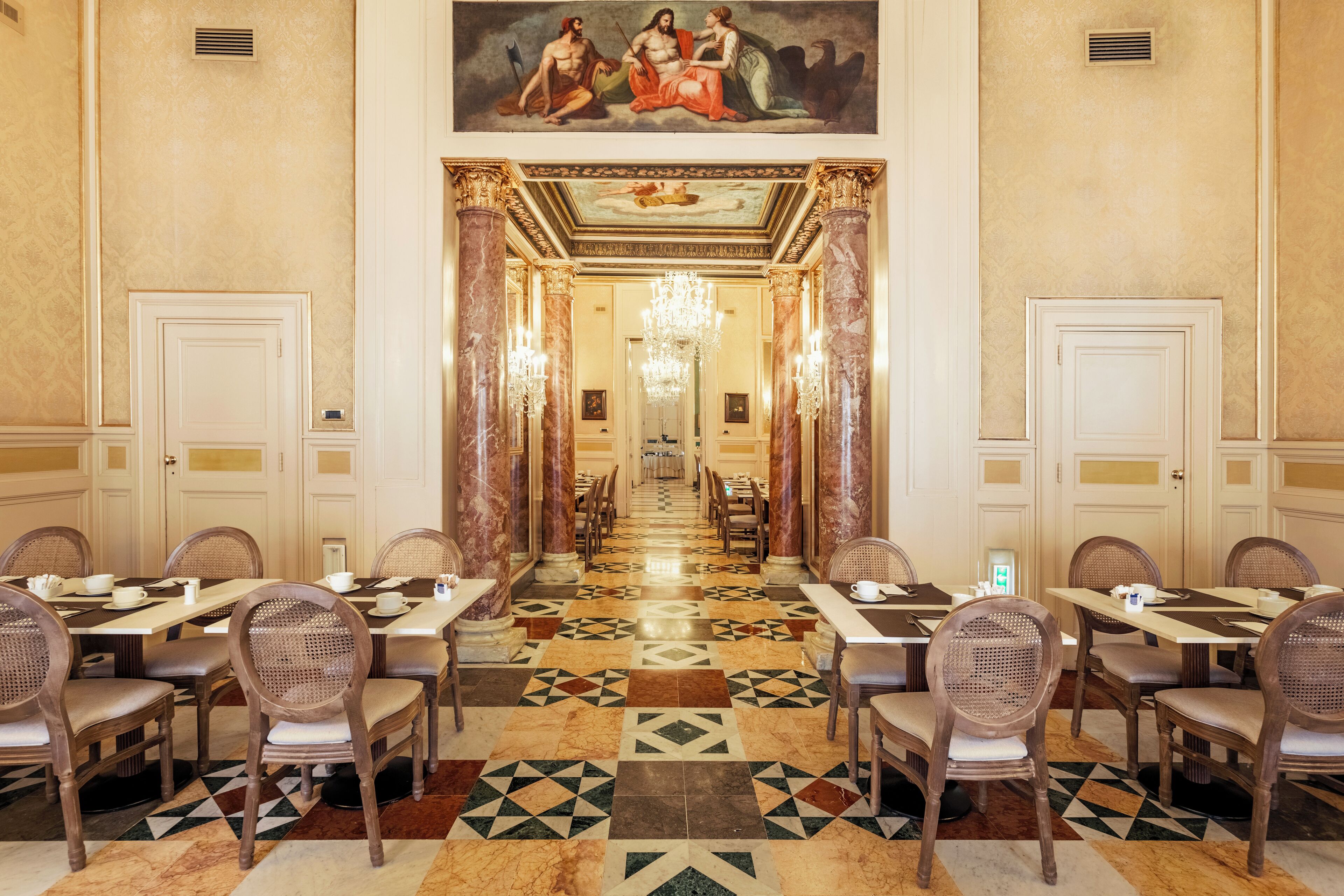 Une salle à manger élégante, avec une longue table, des chaises et un sol à motifs.