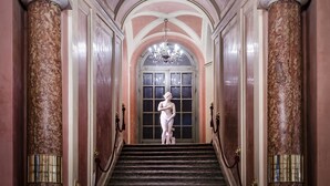 Una imponente escalera con columnas de mármol y una estatua en la parte superior.