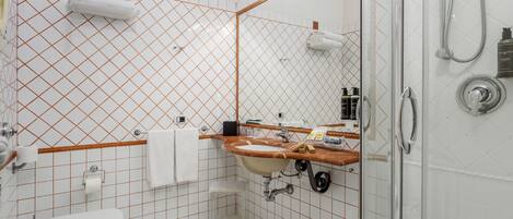 A bathroom with a white toilet, sink, and shower. There are towels hanging on the wall and a mirror above the sink.