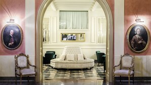 Um hall imponente com uma grande porta em arco, um sofá estofado e duas cadeiras ornamentadas.