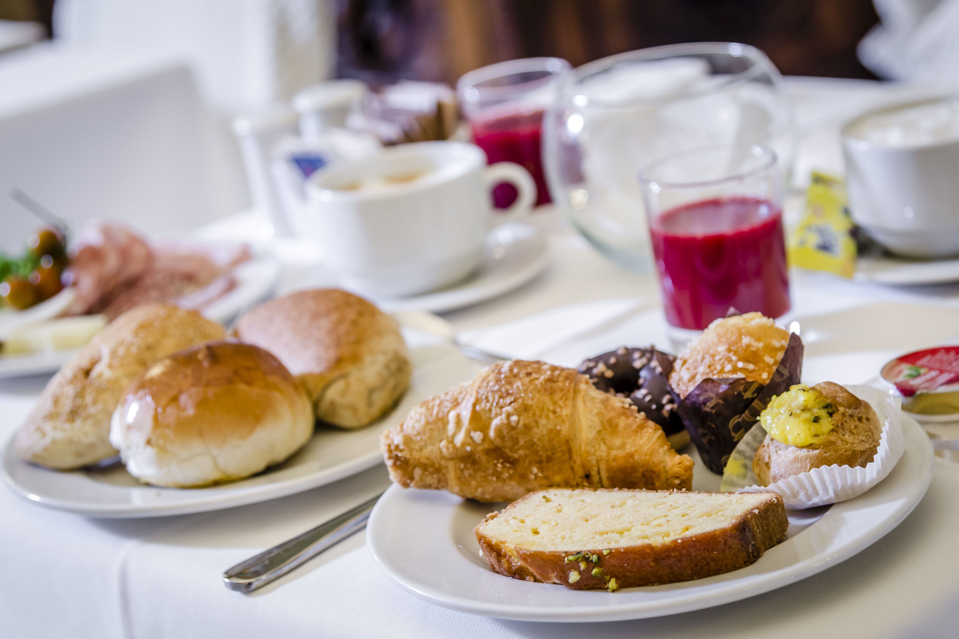 A breakfast setting with pastries, bread, and beverages on a table.