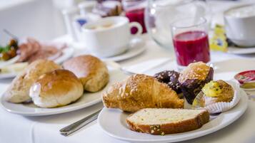 Una colazione con dolci, pane e bevande su un tavolo.