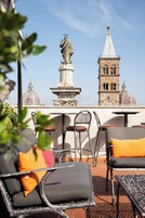 Tavoli all'aperto con vista su una torre storica e cupole.