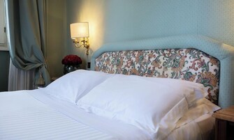 A neatly made bed with white linens in a hotel room.