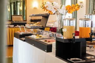 Un'area buffet con diverse opzioni di cibo, una postazione caffè e fiori decorativi.