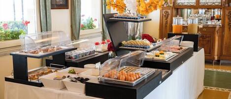 A buffet setup with various food items in clear containers, a decorative vase with flowers, and a wooden cabinet in the background.