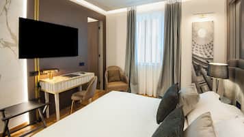 A hotel room with a bed, desk, chair, TV, and artwork.