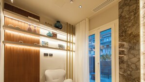 Un interior moderno con un sillón blanco, un panel de madera y un vidrio que da a un balcón exterior.