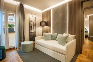 A modern living room with a sofa, ottoman, and a lamp.