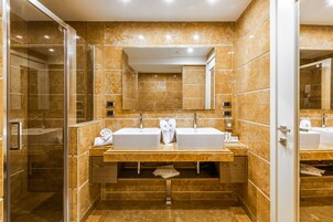 A modern bathroom with two sinks, a large mirror, and a glass shower enclosure.