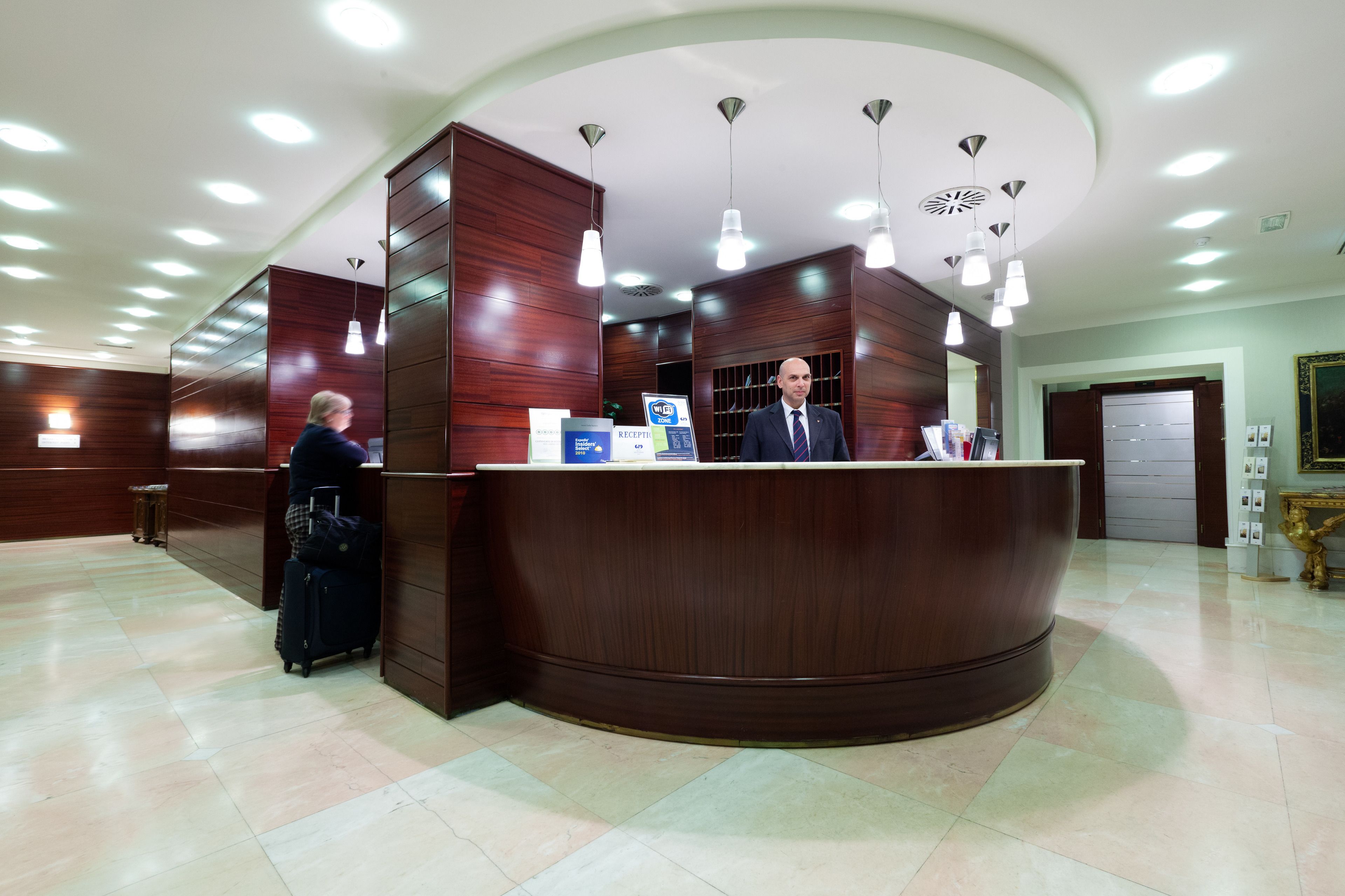 A reception area with a curved wooden counter, multiple pendant lights, and a tiled floor.