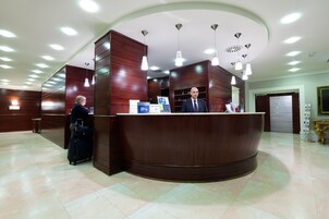 A reception area with a curved wooden counter, multiple pendant lights, and a tiled floor.