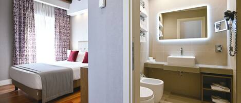 Une chambre d’hôtel moderne, équipée d’un lit, d’une salle de bain avec un lavabo et d’un miroir.