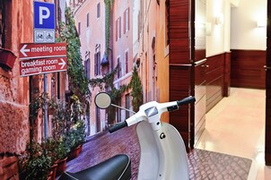 En scooter parkeret foran en bygning med et skilt, der viser et mødelokale til venstre og et morgenmadsrum til højre.