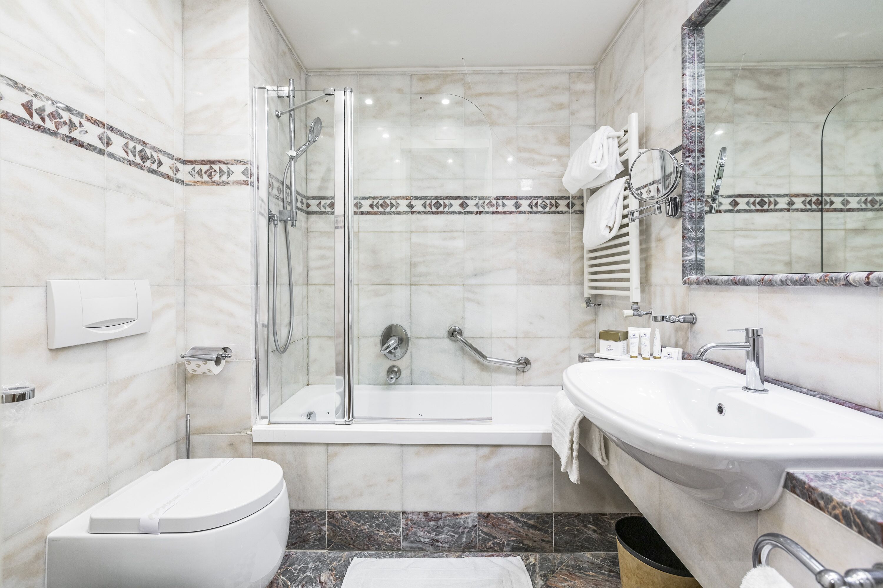 A modern bathroom with a glass-enclosed shower, a white toilet, a sink, and a mirror.