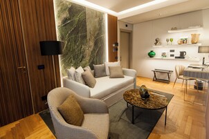 A modern living room with a sofa, armchair, coffee table, and a marble accent wall.