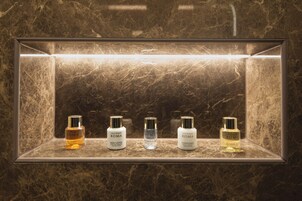 A marble-tiled shelf with five bottles of Laura Biaggi Roma products: hair shampoo, body lotion, intimate care, and shower gel.