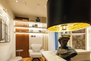 A modern interior with a white armchair, a bust sculpture, and a black lamp with a yellow shade.