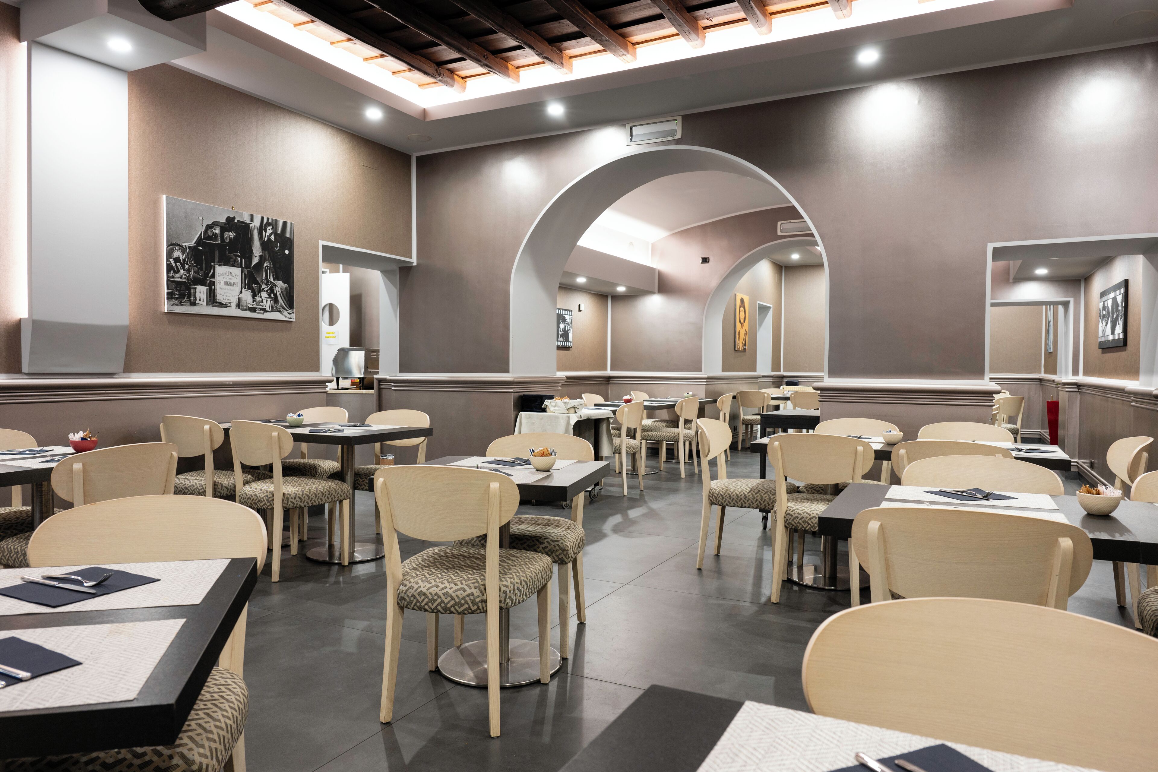 Un comedor moderno con varias mesas y sillas, un tragaluz y obras de arte en las paredes.