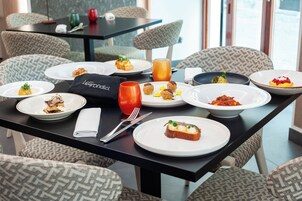 A dining table set with various dishes, a glass of orange juice, and a napkin with a logo.