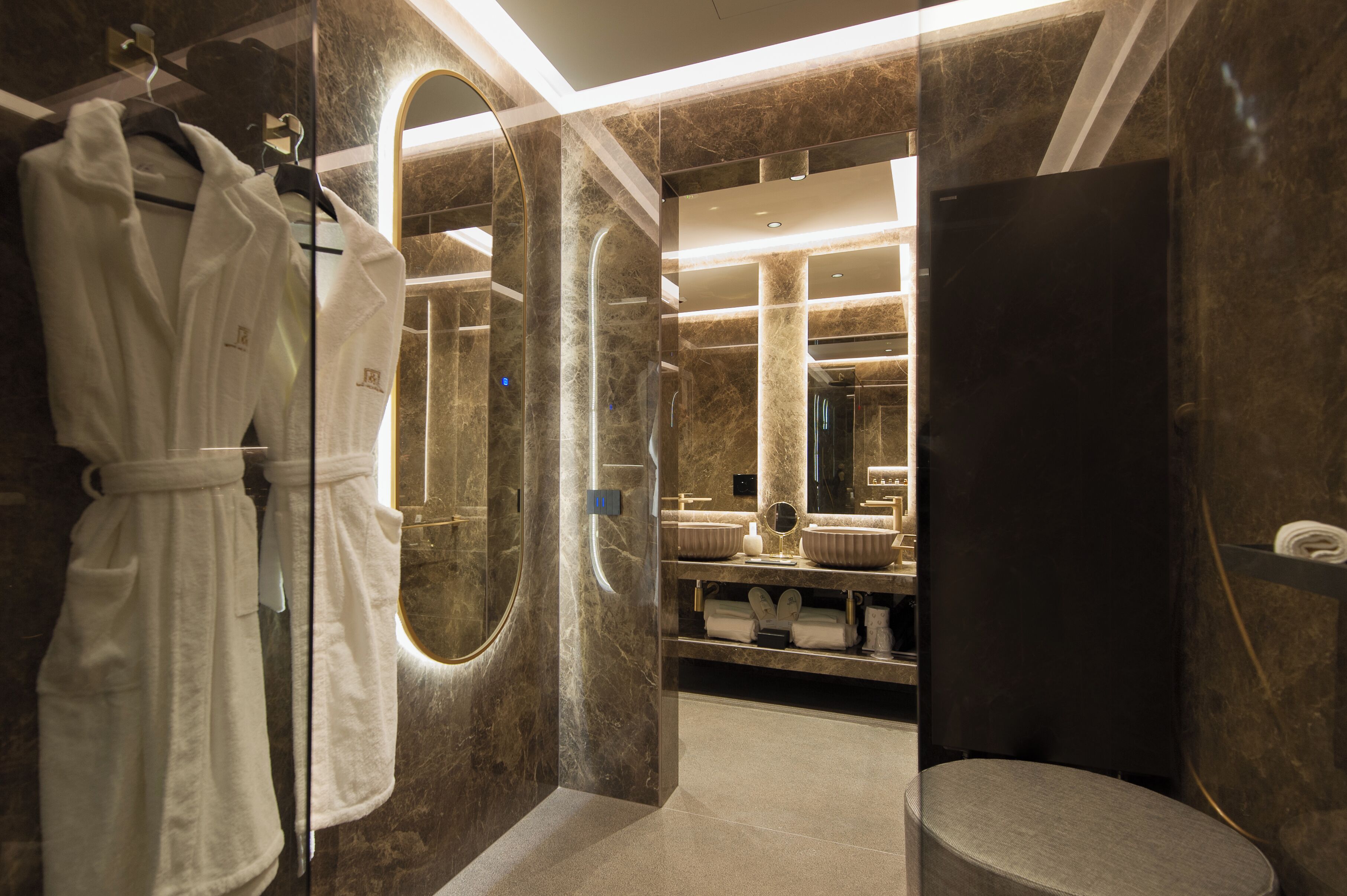 A modern bathroom with a large mirror, a vanity with a sink, and a robe hanging on a rack.