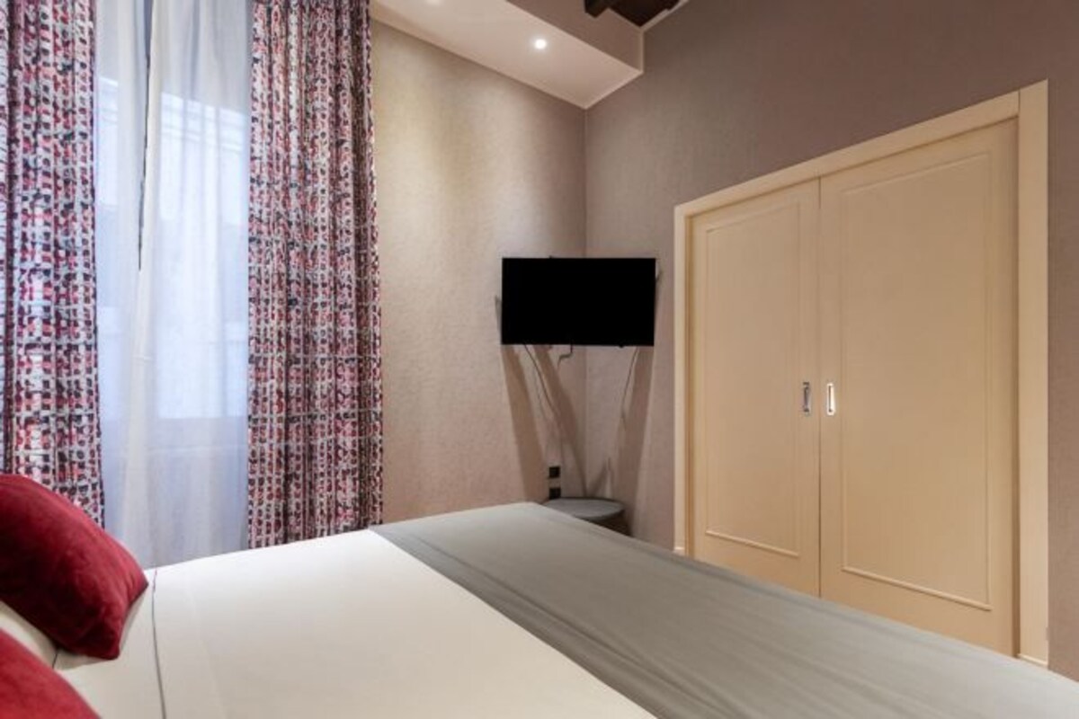 Un dormitorio con una cama, un televisor y un armario.