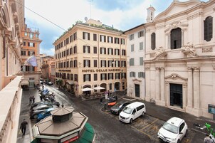 A street view of Hotel delle Nazioni with a central building, a covered outdoor seating area, and a parked white van.
