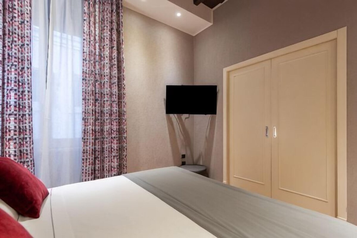 A bedroom with a bed, a TV, and a wardrobe.