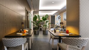 Un comedor moderno con sillas estampadas, mesas y plantas en macetas.