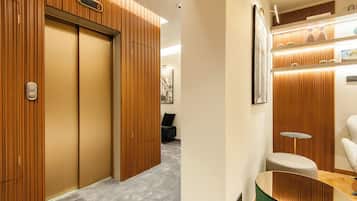 A hotel room with wooden paneling, a grey carpet, a small round table, and a green ottoman.